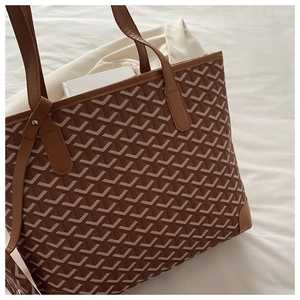 Close-up of brown tote bag with classic Y-pattern print and premium leather handles