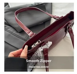 Détail de la fermeture éclair métallique et dentelle blanche sur le sac Boston bordeaux