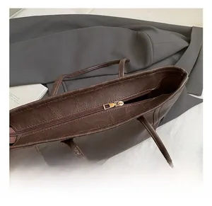 Gros plan sur la fermeture éclair dorée et le cuir marron texturé d'un grand sac cabas