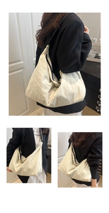 Detail of large beige nylon tote bag featuring black zipper and adjustable wide strap