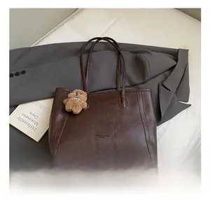 Détail du grand sac cabas marron foncé avec pendentif ours et logo imprimé