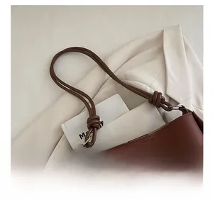 Detail of dark brown leather tote bag showing knotted shoulder strap and texture