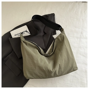 Close-up of olive green nylon pillow bag with black wide strap and zipper detail