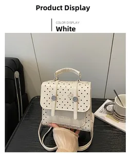 Close-up of white polka dot PU leather bag with dual buckle closure and handle