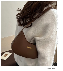 Chic caramel brown crescent moon bag shown on a shoulder with a cozy white knit sweater