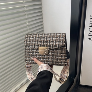 Sac bandoulière rétro à carreaux avec fermoir doré et large sangle fleurie tenu en main