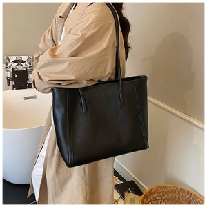 Détail du sac cabas noir avec logo embossé et finitions de couture élégantes