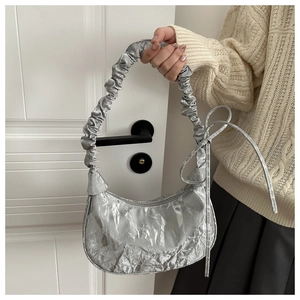 Close-up of a silver crescent bag with unique pleat textures and side ribbon detailing