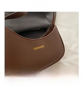 Macro shot of dark brown matte leather texture and gold lettering on the crescent bag