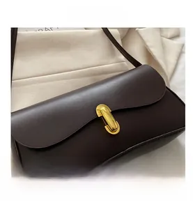 Detail of a dark brown leather handbag featuring a vintage oval gold metal twist lock