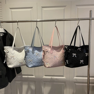 Quilted tote bags with bow embroidery in white, blue, pink and black hanging on a rack