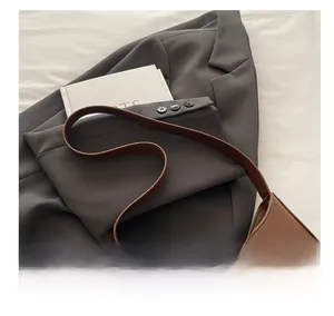 Minimalist brown faux leather hobo bag with gold lettering shown on a grey blazer