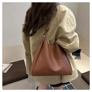 Brown leather tote bag featuring a metallic buckle strap detail and spacious interior
