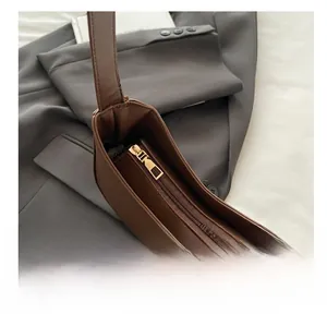 Close-up of golden zipper hardware and brown leather stitching on crescent shoulder bag