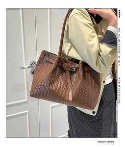 Detailed close-up of brown woven leather tote bag with stylish side buckle and long straps