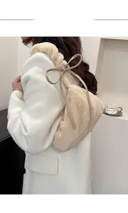 Close-up of cream faux fur shoulder bag with decorative bow strap on female model