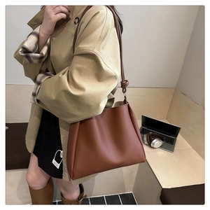 Detailed view of brown leather tote bag with knot strap detail and large capacity