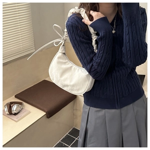 Detail of white dumpling bag with pleated cloud strap and side ribbon bow decoration