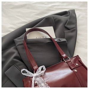 Détail du sac cabas en simili cuir bordeaux avec nœud en dentelle et rivets argentés