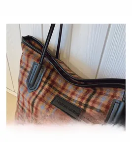 Detail of vintage plaid tote bag with FASHION & BAGS leather patch and black handles