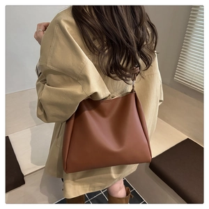 Detailed close-up of brown faux leather shoulder bag worn with a casual beige jacket