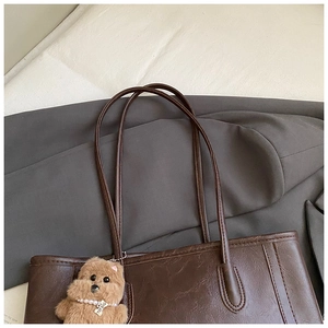 Détail d'un cabas en cuir marron foncé avec un charmant chien en peluche et perles