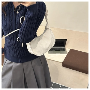 Detail of white hobo bag with unique pleated ruched strap and minimalist side logo