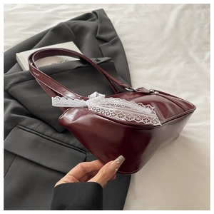 Détail du sac sous le bras vintage bordeaux avec nœud en dentelle blanche et bouton en métal
