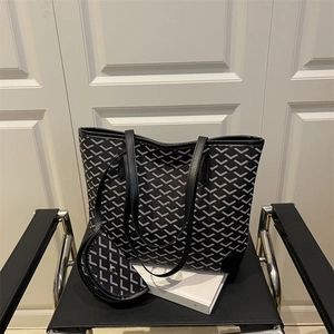 Chic black and white geometric tote bag set with matching pouch on a luxury leather chair