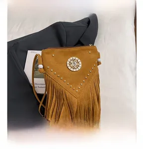 Detail of bohemian suede crossbody bag with rivets, fringe, and circular crystal ornament