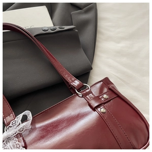 Détail du sac Boston en cuir verni bordeaux avec un nœud en dentelle blanche et rivets