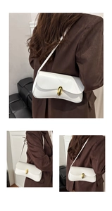 Detail of white matte leather underarm bag featuring a golden oval clasp for women