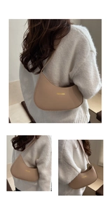 Detail of minimalist beige half-moon shoulder bag worn over a white knitted sweater
