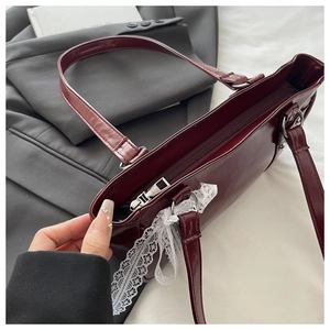 Détail d'un sac Boston bordeaux brillant en PU avec dentelle blanche et zip métallique