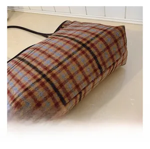Detail showing the retro plaid wool texture and reinforced bottom of the tote bag