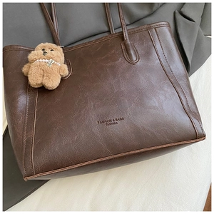Détail du grand sac cabas marron foncé à texture cirée vintage et pendentif ours