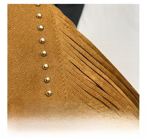 Detail shot of brown suede texture with stylish gold studs and bohemian tassel trim