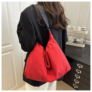 Modern red waterproof nylon hobo bag shown worn on back with black wide shoulder strap