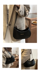 Detail of black crescent shoulder bag with golden logo lettering in a cafe setting
