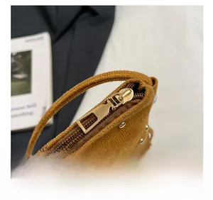 Macro detail of smooth golden zipper and rivet accents on a brown suede fringe bag