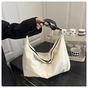 Detail of white nylon hobo bag showing large capacity, black strap, and metal zipper