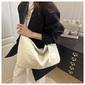 Grand sac hobo blanc crème avec bandoulière noire réglable porté par un mannequin