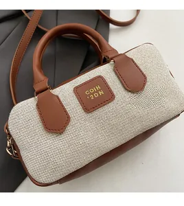 Detail view of canvas bowling bag with brown leather trim and embossed square logo