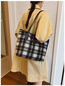 Gros plan d'un sac cabas à carreaux noir et blanc avec poignées en cuir sur un mannequin