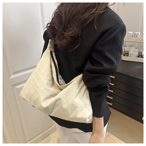Detail of a large cream tote bag with textured soft fabric and black zipper closure