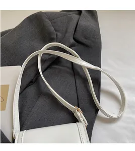 Detail of adjustable white synthetic leather shoulder strap with light gold metal hardware