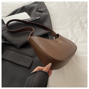 Close-up of deep brown crescent hobo bag featuring gold lettering and smooth leather texture