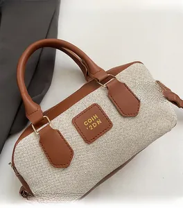 Close-up of contrast stitching on canvas and brown leather Boston bag with metal rings