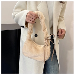 Detail of plush apricot underarm bag with pleated handle and faux fur texture on a model