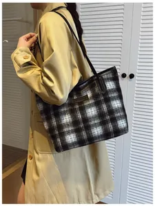Sac cabas à carreaux tendance avec bandoulière porté par un mannequin en trench